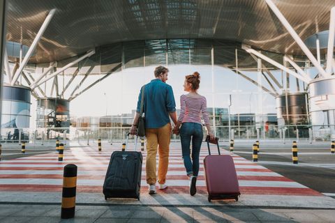 Beautiful loving couple with travel suitcases holding hands in airport