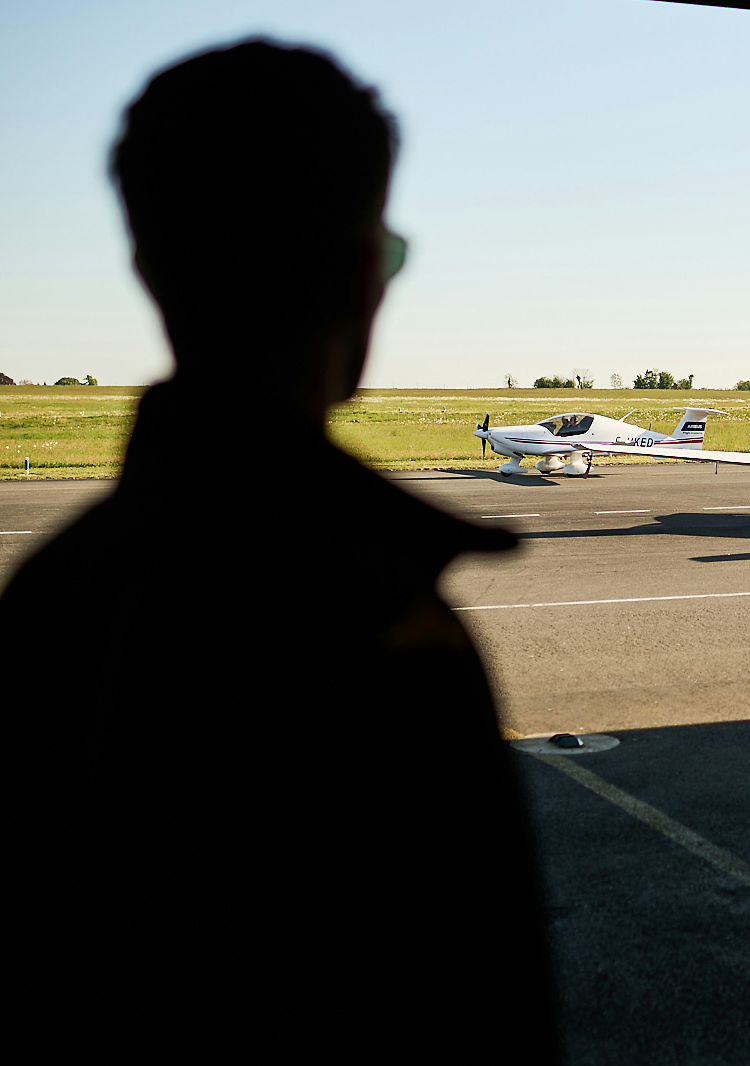 AFA - Cadet from behind looking at an aircraft Cadet seen from behind looking at a Cirrus SR20 Airbus Flight Academy aircraft on sunny Angoulême's airport tarmac